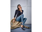 Une femme porte un pull noir, un jean bleu et des chaussures noires.