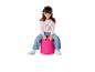 Petite fille souriante assise sur un pouf rose, portant un pull rose avec une licorne et un jean.