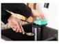 Mains lavant une cuillère dans un évier de cuisine avec une éponge et un distributeur de savon.