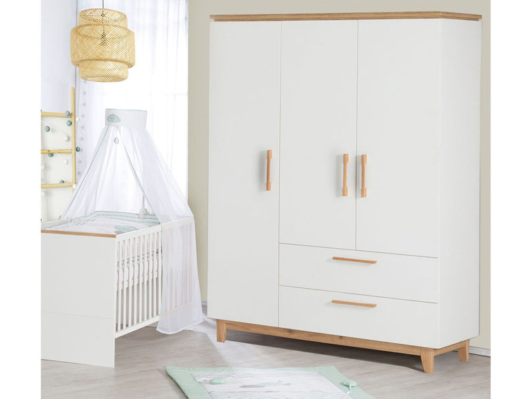 Un lit bébé blanc avec un ciel de lit et une armoire blanche avec des détails en bois.