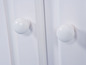 Deux boutons blancs sur une porte de placard blanche.