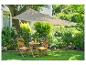 Parasol beige et mobilier de jardin en bois dans un jardin fleuri.