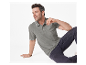 Un homme porte un polo gris et un jean foncé.