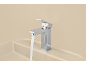 Robinet chromé avec de l'eau qui coule sur un lavabo beige