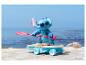 Figurine Stitch sur skateboard avec pagaie, sur une plage.