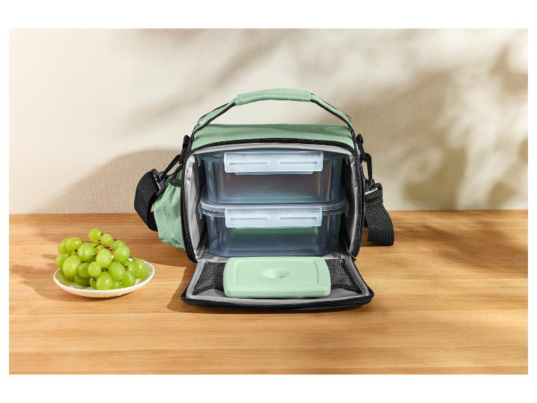 Sac isotherme avec récipients alimentaires et raisins sur une table en bois.