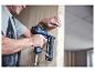 Homme utilisant une agrafeuse/cloueuse pneumatique pour fixer des panneaux de bois.