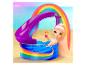 Poupée aux longs cheveux roses dans une piscine thème arc-en-ciel avec toboggan sur une plage de sable.
