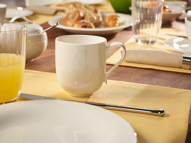 Table de petit-déjeuner avec une tasse blanche, du jus d'orange et des pâtisseries sur une table en bois.