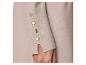 Manche de pull beige avec boutons dorés et manchette fendue.