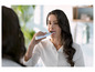 Une femme se brosse les dents avec une brosse à dents électrique Oral-B.