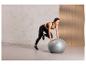 Une femme fait des exercices avec un ballon de fitness gris de Crivit.