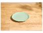 Assiette vert clair sur une table en bois clair avec des ombres