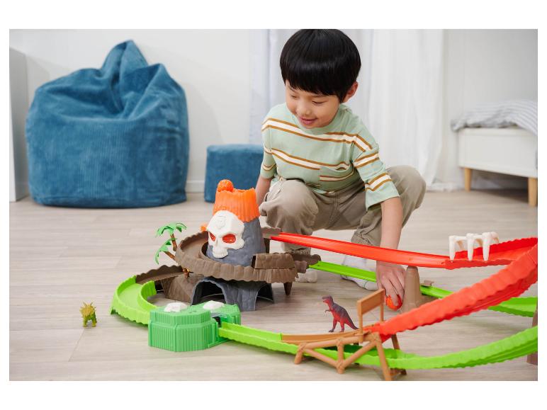Un garçon joue avec un ensemble de jeu sur le thème des dinosaures et du volcan.
