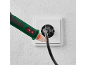 Un testeur de tension vert et noir est utilisé pour vérifier une prise électrique blanche.