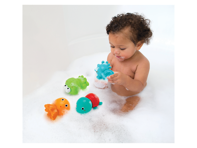 Bébé joue avec des jouets de bain : grenouille, tortue et poulpe.