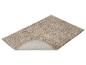 Tapis de bain beige avec un bord relevé montrant le dessous antidérapant.