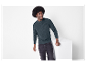 Homme avec une coiffure afro portant un pull vert foncé et un jean noir.