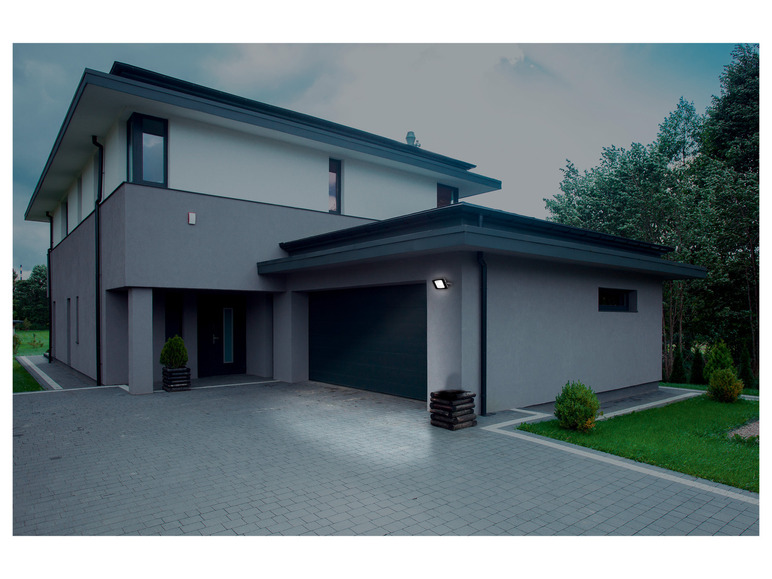 Une maison moderne avec une porte de garage et un éclairage extérieur.