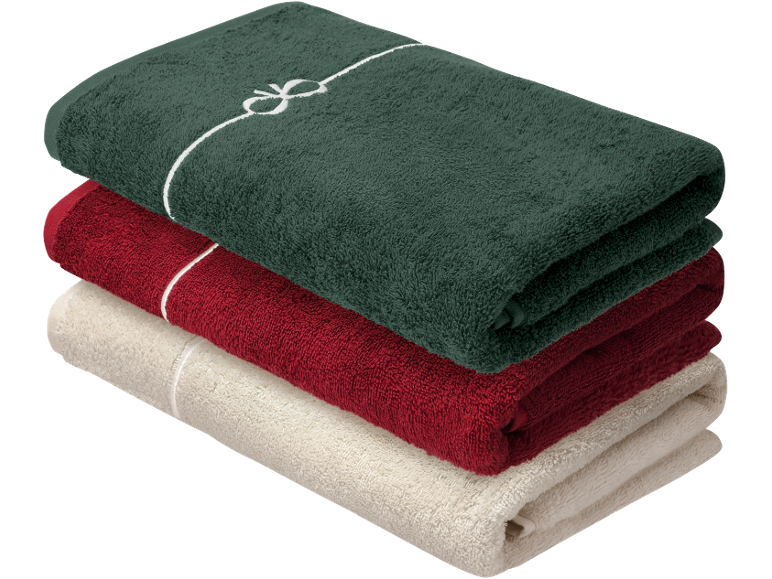 Pile de serviettes pliées vert foncé, rouge et beige, la supérieure avec un nœud blanc.