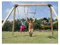 Enfants jouant sur une balançoire en bois avec anneaux et siège, sur un champ vert.