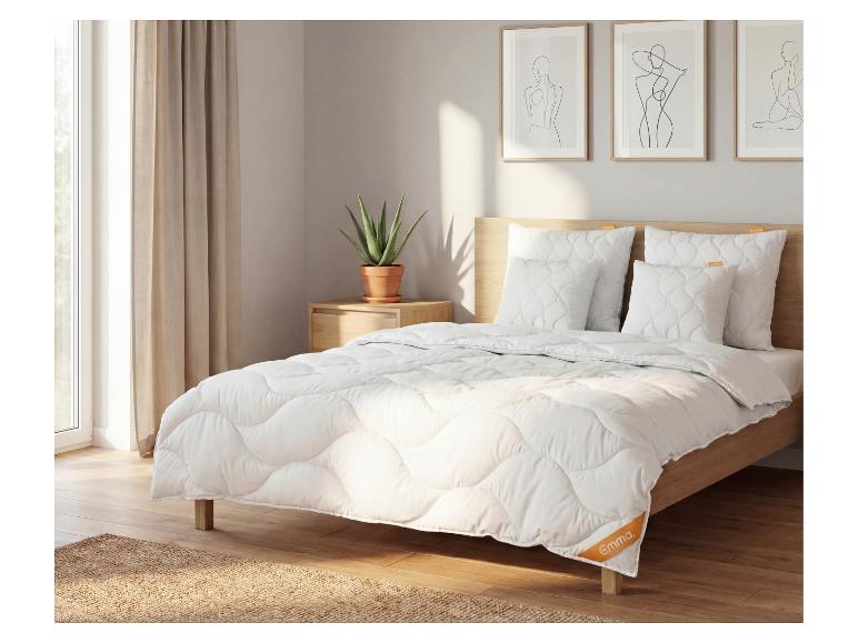 Chambre avec un lit doté d'une literie matelassée blanche, d'oreillers et d'une tête de lit en bois.