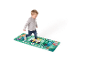 Un enfant joue sur un grand tapis de piano au sol avec des personnages de dessins animés et des notes de musique.