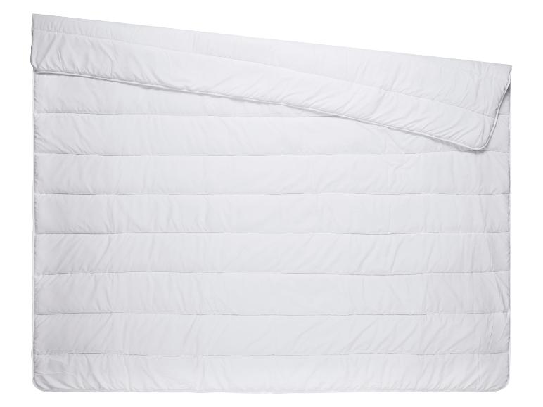 Couette blanche avec matelassage horizontal, partiellement pliée dans le coin supérieur gauche.