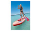 Une femme pagaye sur un paddleboard gonflable rose dans une eau turquoise.