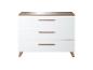 Commode blanche à trois tiroirs avec poignées en bois et plateau en bois.
