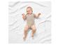 Bébé souriant sur une couverture blanche, vêtu d'un body beige.
