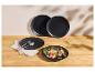Assiettes noires mates avec couverts et salade de fruits rouges sur une table en bois.