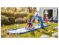 Enfants jouant sur un toboggan aquatique gonflable avec arche de requin dans un jardin ensoleillé.