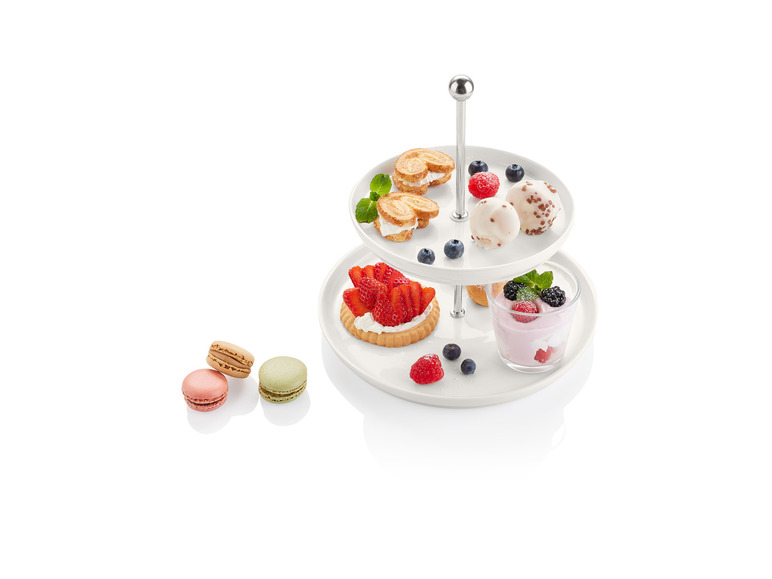 Plateau de service à deux étages avec diverses gourmandises, dont des pâtisseries, des macarons et des fruits.