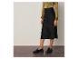 Une femme portant une jupe en satin noir et des mocassins noirs.