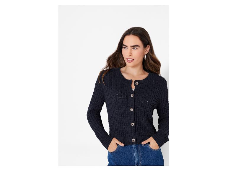 Une femme porte un pull en tricot bleu foncé avec des boutons.