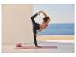 Femme en tenue de yoga exécutant la pose du danseur sur un tapis de yoga avec des blocs.