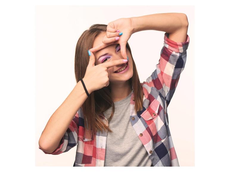 Femme souriante en chemise à carreaux, encadrant son œil avec ses mains.