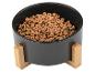 Gamelle noire pour animaux de compagnie avec support en bois, remplie de croquettes.