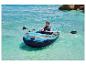 Un homme pagaye sur une mer turquoise dans un bateau pneumatique Crivit.