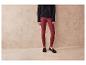 Une femme portant un pull noir et un legging rouge foncé avec des mocassins noirs.
