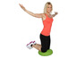 Une femme en tenue de sport fait des exercices sur un disque d'équilibre vert.