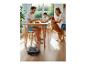 Robot aspirateur nettoyant le sol pendant qu'une famille déjeune avec son chien.