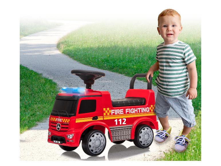 Un jeune enfant avec un camion de pompiers jouet Mercedes-Benz.