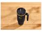 Mug thermique noir avec anse et paille, avec des accents dorés, sur une table en bois.