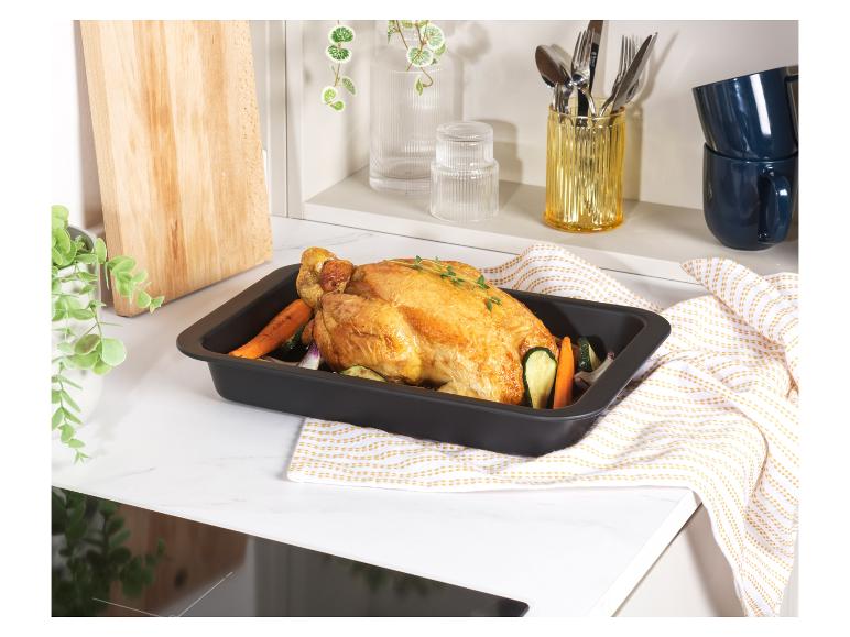 Un poulet rôti avec des légumes dans un plat allant au four noir.