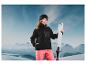 Une femme avec une veste en polaire noire et des skis dans un paysage d'hiver