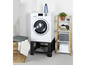 Une machine à laver avec un socle noir, un panier à linge en bois et une étagère blanche avec des serviettes