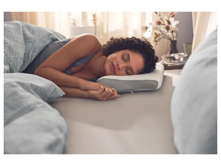 Une femme dort sur un oreiller ergonomique multifonctionnel LIVARNO.