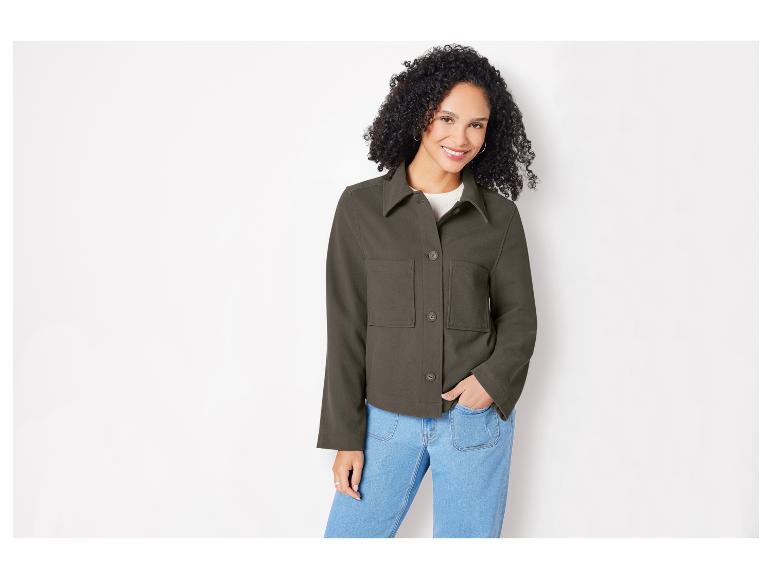 Une femme portant une veste vert foncé et un jean bleu.